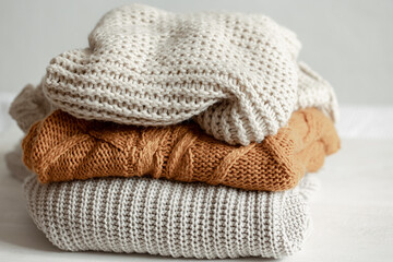 Fototapeta na wymiar A stack of warm knitted sweathers on blurred background.