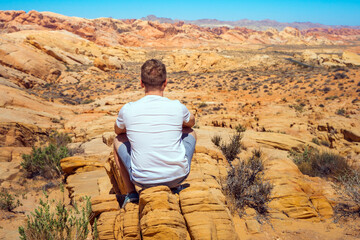 A young man enjoys a beautiful desert landscape in the Valley of Fire National Park, Nevada