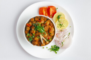 Chickpeas masala (Spicy chola or chhole curry)  garnished with fresh green coriander and ingredients. Served in a ceramic bowl. An Classic Indian typical Panjabi street food.  