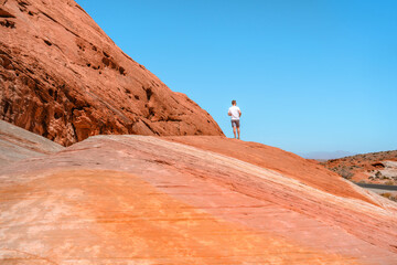 A young man stands on a high rock in the Valley of Fire National Park, Nevada