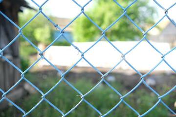 Metallic blue mesh on a green blurred background. Selective focus. Blue grid