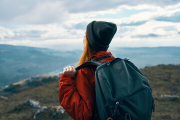 energetic woman in warm clothes with backpack travel tourism mountains landscape back view