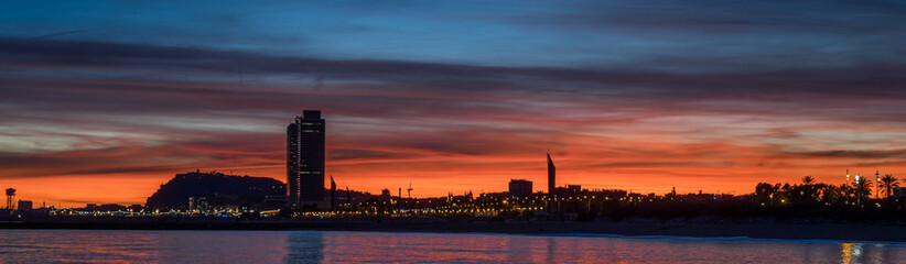 Fototapeta na wymiar atardecer con cielo anaranjado y luces de la ciudad de barcelona 