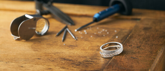 Golden Ring and jeweller tools on an antique wooden desktop. Jeweller, engraver at work on jewelry...