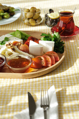 Delicious traditional turkish breakfast on yellow checkered tablecloth.
Tea, olives, eggs, cheeses, cucumbers, tomatoes