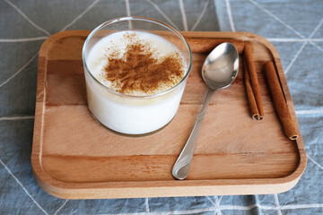 Rice pudding with cinnamon in glass bowl on wooden stand
