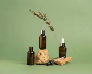 A bottle of serum oil cosmetic on an abstract podium made of natural materials stones plants green...