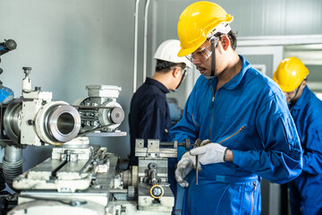 Asian male mechanical worker working on milling machine in workshop.