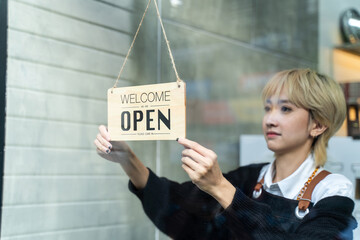 Asian female hairdresser hanging Welcome, We are open sign on the door