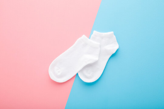 Two white short socks on light blue pink table background. Pastel color. Closeup. Top down view.