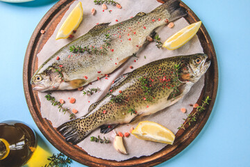 two raw rainbow trouts on paper with thyme and lemon. Fish trout. Top view. Free space for your text.