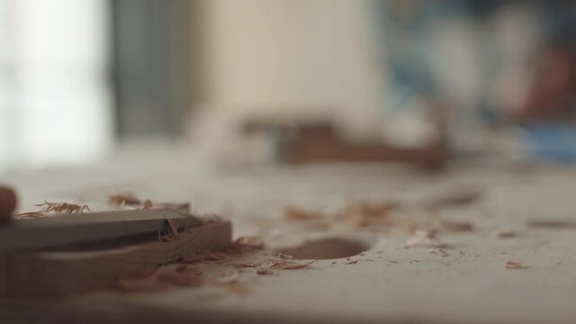 Macro of unrecognizable female joiner carving piece of timber with chisel in workshop