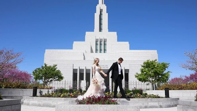 Young Bride And Groom Walking In Front Of Modern White Church Building