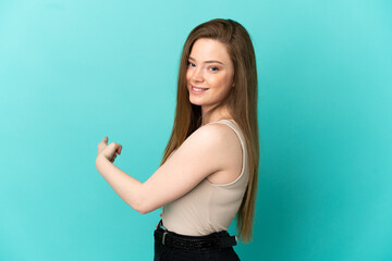 Fototapeta premium Teenager girl over isolated blue background pointing back