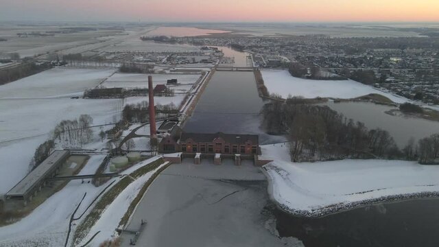 Industrial water pumping station in Friesland at Ijsselmeer lake, dawn