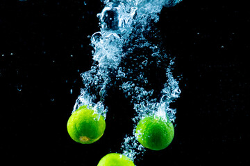 Lemon drop into the water, motion action. On a black background, soft focus.