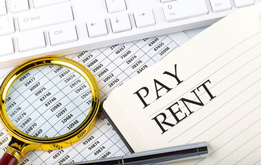 PAY RENT text on notebook with chart, magnifier,keyboard and pen
