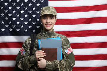 Female soldier with backpack and notebooks near flag of United States. Military education