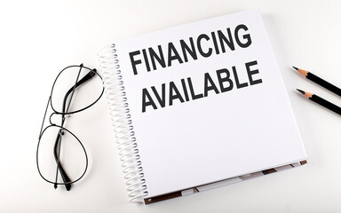 Notebook with text FINANCING AVAILABLE on white background