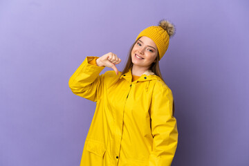 Teenager girl wearing a rainproof coat over isolated purple background proud and self-satisfied
