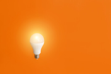 the included electric lamp shines on an orange background copy space