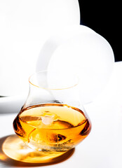 Whiskey, scotch or bourbon glass with ice on black and white background with geometric cubes and circles. Contemporary still life