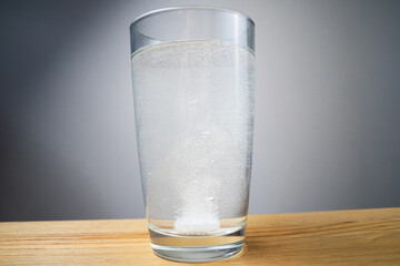 The tablet dissolves in a glass on a wooden table close-up.