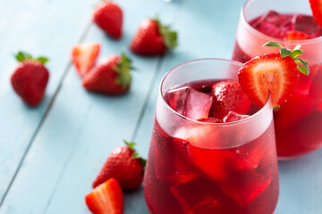Strawberry cocktail in glass on blue wooden table. Copy space