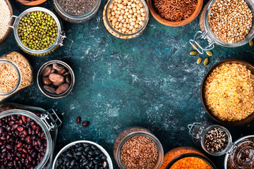 Various organic superfoods, beans, grains, cereals, legumes, seeds in reusable cans and jars. Copy space top view. Blue background