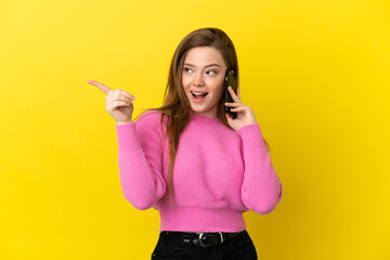 Teenager girl using mobile phone over isolated yellow background intending to realizes the solution while lifting a finger up