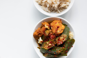 Okra, Hähnchen scharf mit Knoblauch und Chilli, Naturreis in Schale, Hintergrund weiß