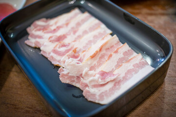 Fresh bacon raw sliced was served for Sukiyaki and Shabu or Yakiniku restaurant which it put on black plate.