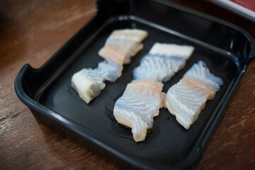 Sliced fresh Dolly fish raw was served for Sukiyaki and Shabu or Yakiniku  restaurant which it put on black plate.