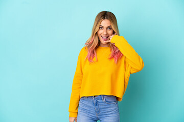 Young woman over isolated blue background making phone gesture. Call me back sign