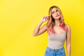 Young woman over isolated yellow background making the gesture of madness putting finger on the head