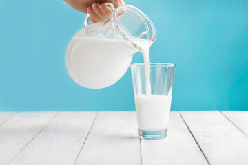 Milk is poured from a jug into a glass. Kefir or vegetable, alternative nut milk. Place for text - obrazy, fototapety, plakaty