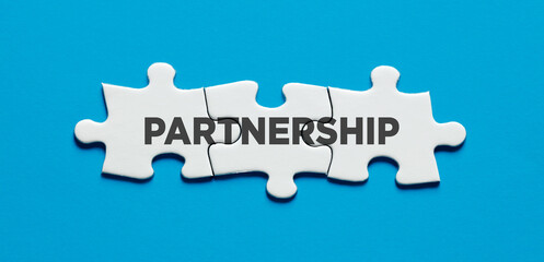 Cooperation, solidarity and support in business. The word partnership on connected puzzle pieces.