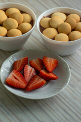 Sweet poudding with small sponge cakes in bols and fresh raw red ripened strawberries, group of fruits cut in halves served