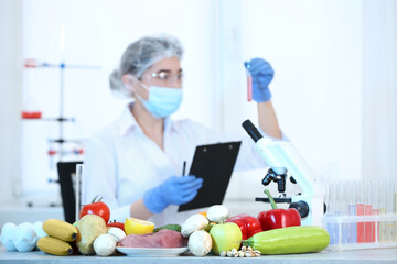 Fresh vegetables, fruits, meat on table and scientist proceeding quality control in laboratory