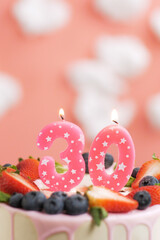 Birthday cake number 30. Beautiful pink candle in cake on pink background with white clouds. Close-up and vertical view