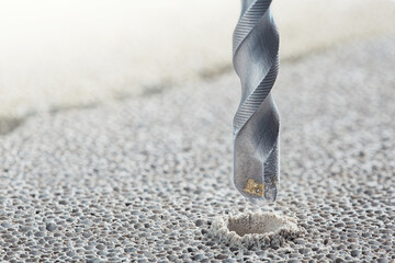 metal drill bit make holes in concrete wall on industrial drilling machine with shavings. Metal...