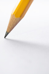 Pencil stands on white paper. The sharp point has just been sharpened. Focus on the black graphite tip. Vertical background image