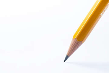 Pencil stands on white paper. The sharp point has just been sharpened. Focus on the black graphite tip. Background image