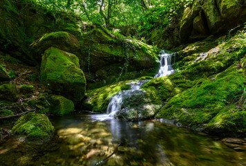 Naklejka na ściany i meble Beautiful Waterfall in the forest. The Secret Waterfalls Eco-trail in Sakar Mountain, Bulgaria at spring. Green forest landscape near Malko Gradishte village 