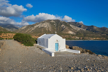 Fototapeta na wymiar a lonely chapel at the mediterranean sea in front of beautiful scenic mountains and gorgeous clouds