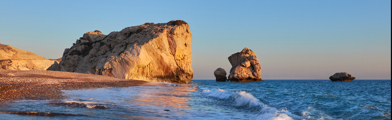 Aphrodite rock Cyprus in soft evening light, curvy waves in the foreground touristic attraction of so called love rock - obrazy, fototapety, plakaty