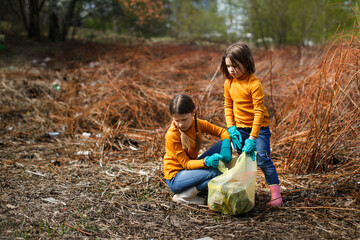 Two children are cleaning in the park, Children with garbage bags pick up garbage in the forest....