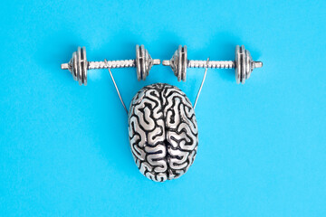 Steel copy of the human brain lifting dumbbells isolated on blue