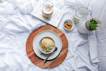 Dalgona coffee with apple oatmeal breakfast on white cozy bed