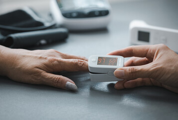 closeup daughter's hand putting oximeter on mom's finger for blood oxygen monitoring